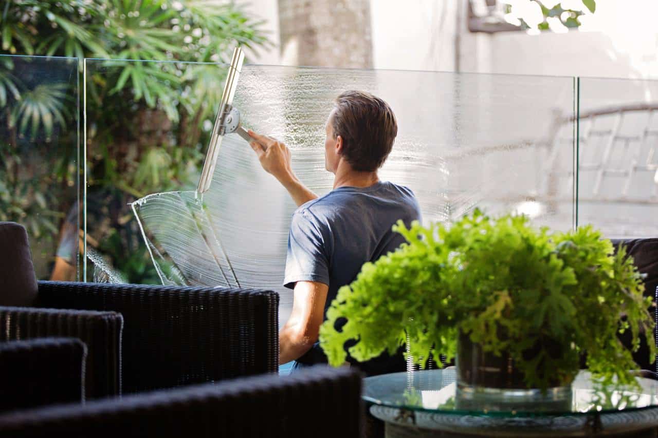 Man in Gray Shirt Cleaning Clear Glass Wall Near Sofa from the post 20 Amazing Ways On How To Simplify Your Life